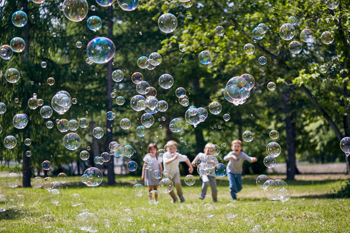 Kinder rennen fröhlich hinter Seifenblasen her
